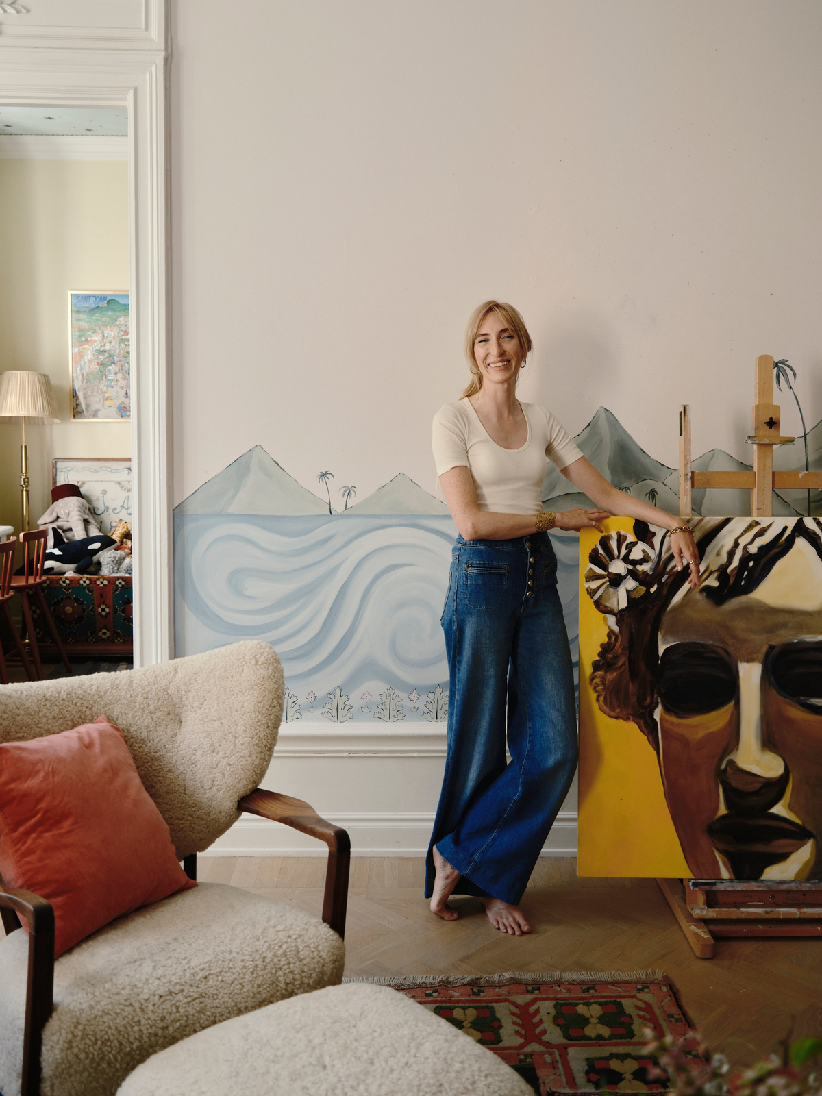 Holly Biörklund standing in her Stockholm studio beside one of her large figurative paintings